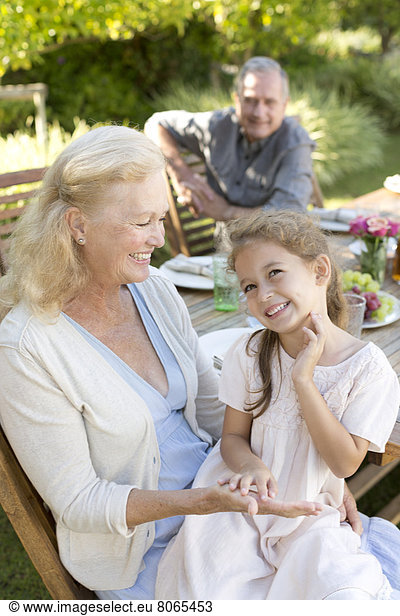 Older woman sitting with granddaughter outdoors