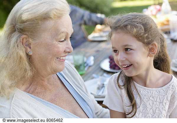 Older woman sitting with granddaughter outdoors