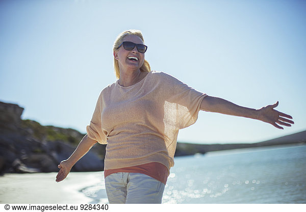 Older woman smiling in sun on beach