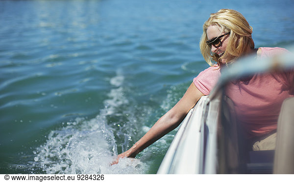 Older woman trailing hand in water from boat