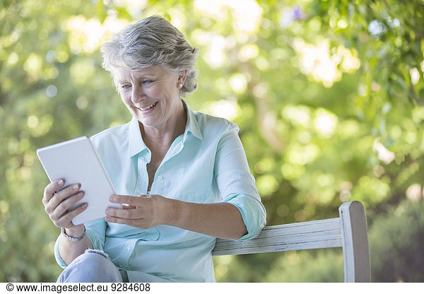 Older woman using digital tablet outdoors