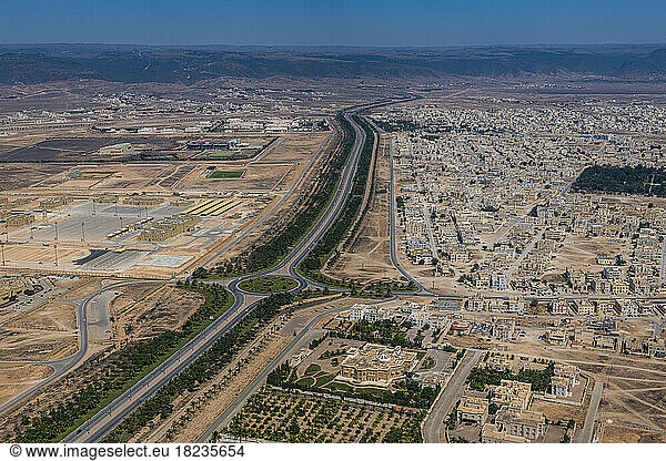 Oman  Dhofar Governorate  Salalah  Aerial view of long road stretching through desert city