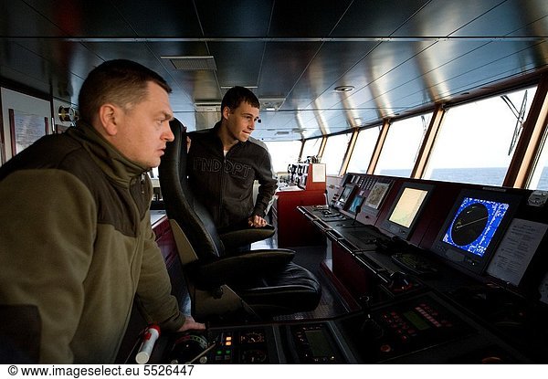 On the bridge of the MV Flintercape a Russian first-officer and a Dutch Cadet study the onboard instruments  during their voyage from Rotterdam  Netherlands to Sundsvall  Sweden.