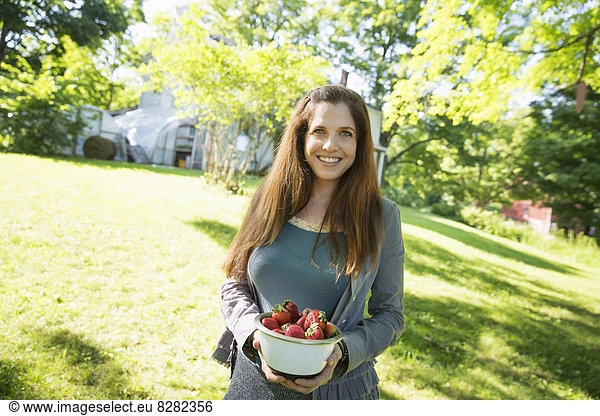 On The Farm. A Woman Carrying A Bowl Of Organic Fresh Picked Strawberries.