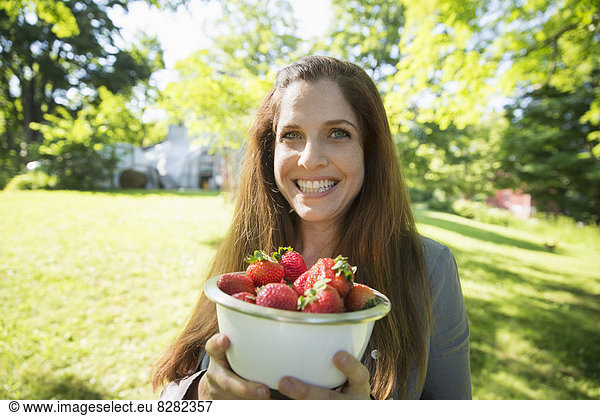 On The Farm. A Woman Carrying A Bowl Of Organic Fresh Picked Strawberries.