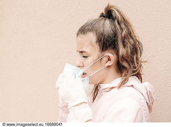 one blonde girl wearing latex gloves and face masks is showing the way she protects herself from coronavirus  bacterias  virus  fungus  etc. She removed mask to take clear breath. Horizontal