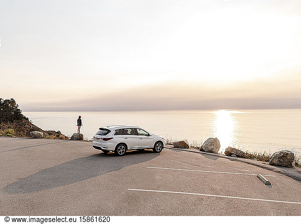 One car parked at Big Sur View point with woman standing on rock