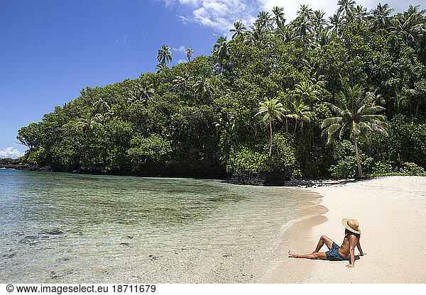 One fit man  wearing hat  tanning on tropical remote beach of Samoa
