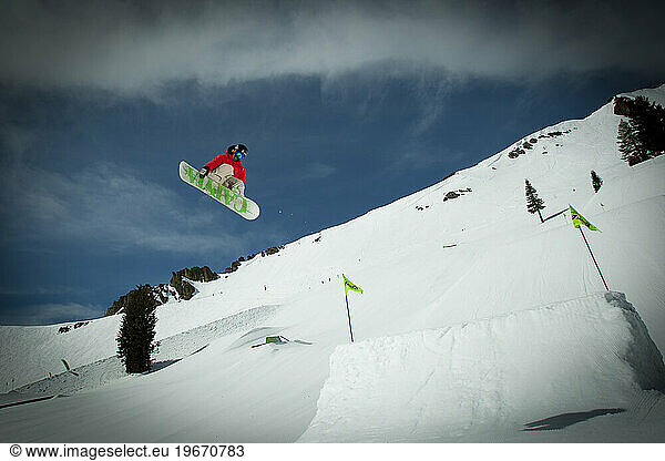 One male snowboarder going off of a big jump at a ski resort