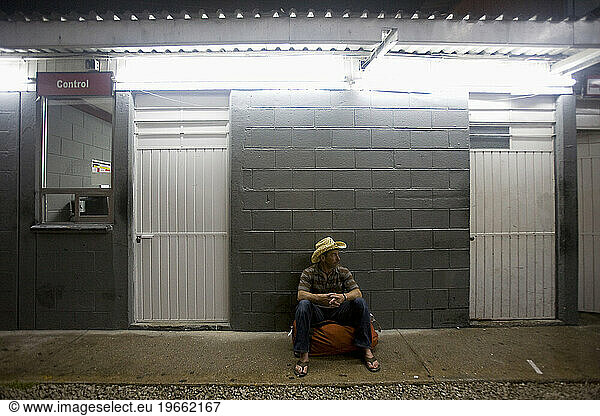 One male traveler sitting on his bag against a wall and waiting for a bus in Mexico.