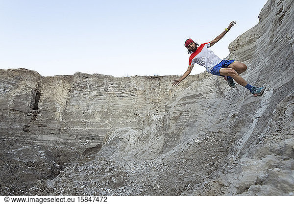 One man preforms a 'wall ride' while trail running on a sandy terrain