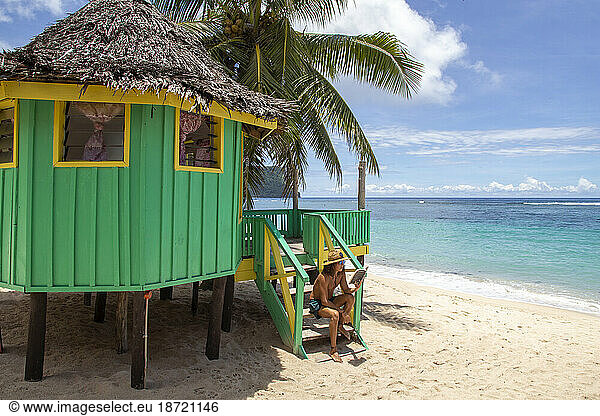 One Man  reading a book on staircase of colorful beach hut  Samoa