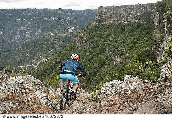 One man riding down a bike on a rocky trail at Peña del Aire