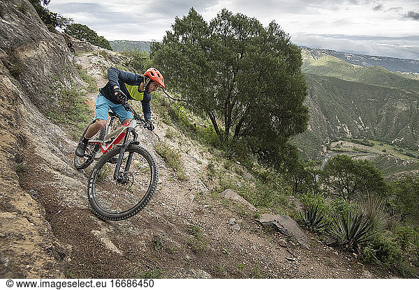 One man riding down a mountain bike on a trail at a canyon