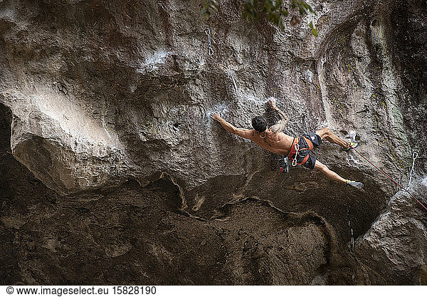 One tattooed man with no shirt stretches while rock climbing in Mexico