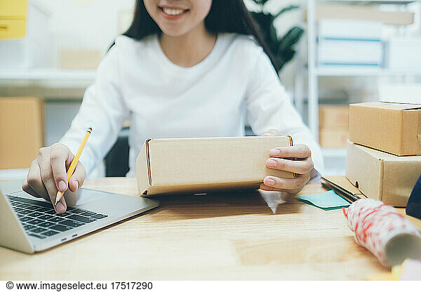 Online small business owner writing address on parcel box.
