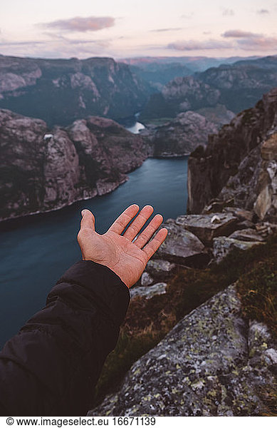 Open hand pointing to Norwegian fjords view at sunset