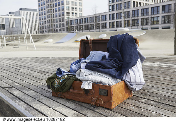 Open suitcase full of clothing on floorboard in playground  Munich  Bavaria  Germany