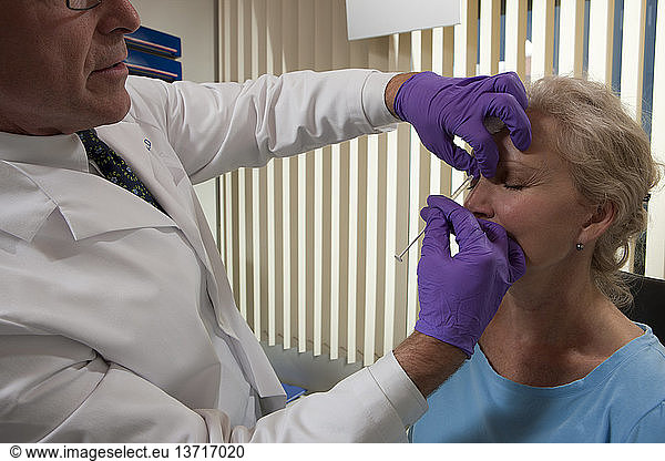 Ophthalmologist giving a Botox injection in glabellar region of the forehead of a patient