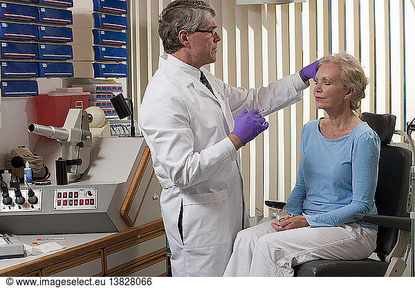 Ophthalmologist giving a Botox injection to a patient with an ice pack