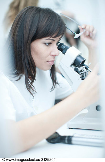 Optician looking through optical equipment