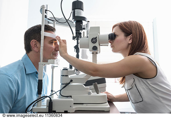 Optiker  der bei Optikern für Kleinunternehmen in die Augen des Patienten schaut