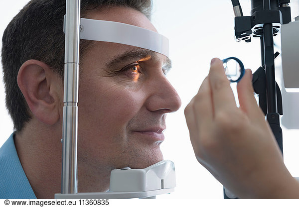 Optiker  der bei Optikern für Kleinunternehmen in die Augen des Patienten schaut