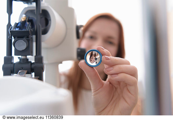 Optiker  der bei Optikern kleiner Unternehmen die Linse vor die Augen des Patienten hält