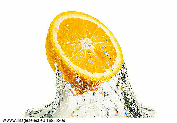 Orange half splashing into water and sinking isolated on white background. Citrus drink concept.