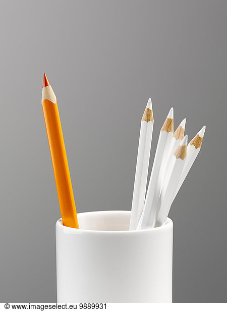 Orange pencil separated in cup with white pencils still life