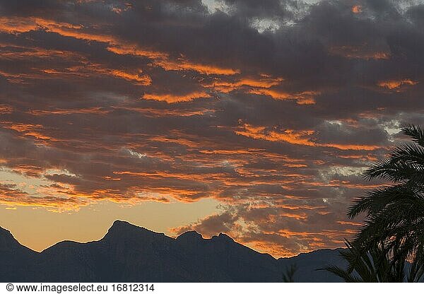 Orangefarbene Wolken bei Sonnenuntergang und das Gelada-Gebirge an der Küste von Altea in der Provinz Alicante in Spanien in der Nähe des Mittelmeers.