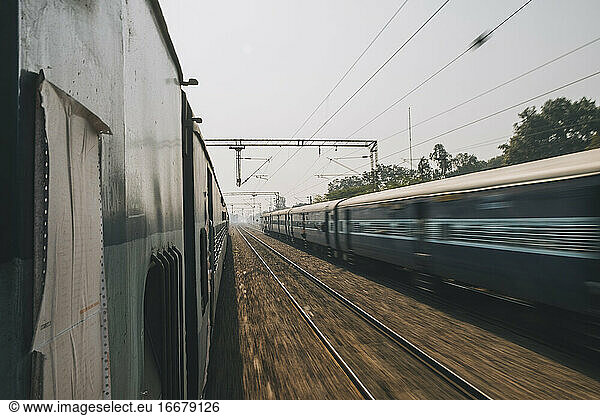 Ordinary express train on a trip from New Delhi to Agra just passing by another train the opposite direction.