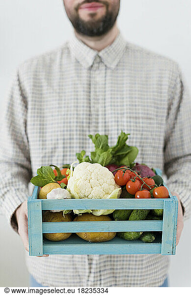 Organic vegetables in crate held by man