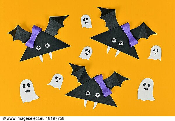 Origami Papier Vampirfledermäuse mit Kulleraugen und Geister und Spinnen auf gelbem Halloween Hintergrund