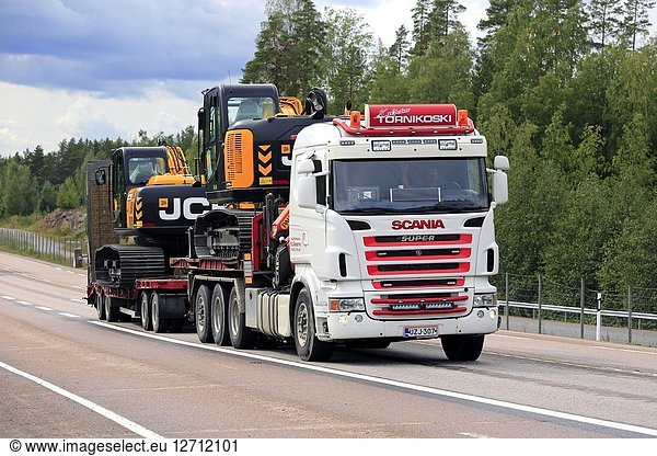 ORIVESI  FINLAND - AUGUST 27  2018: Super Scania truck of Kuljetus Tornikoski Oy hauls two new mid-size JCB excavators along highway in late summer.