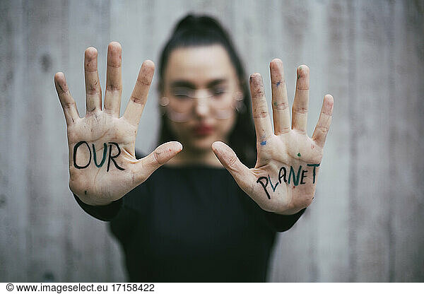 Our planet text written on palms of female activist