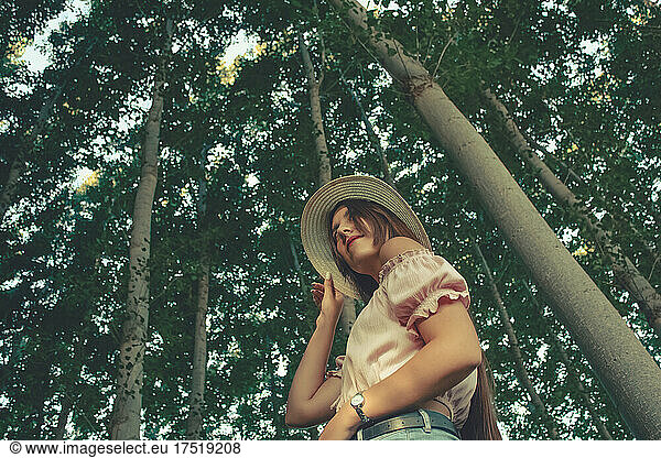 Outdoor portrait in down perspective of a young pretty brunette girl wearing a sun hat