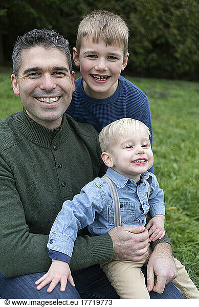 Outdoor portrait of a father with two young sons; Aldergrove  British Columbia  Canada