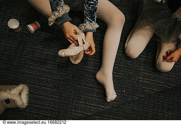 Overhead-Aufnahme eines Kindes beim Anziehen eines Ballettschuhs