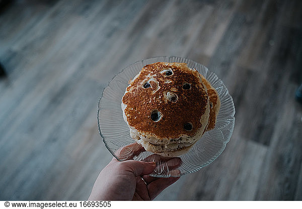 overhead of a person holding a plate of pancakes