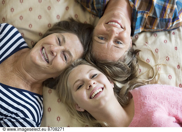Overhead portrait of happy three generation females lying on bed