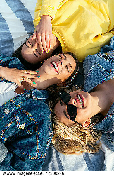 Overhead portrait of smiling friends having fun lying on the beach