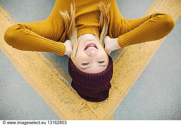 Overhead portrait of young woman lying on yellow road marking