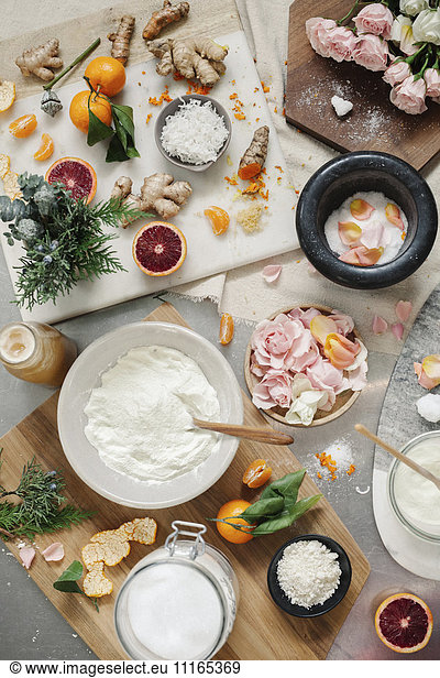 Overhead view of a pestle and mortar and rose petals  ginger and oranges