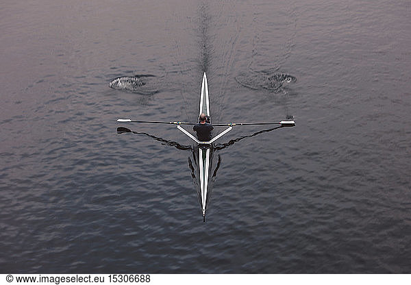 Overhead view of an oarsman in a single scull boat on calm water mid stroke  motion blur.