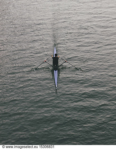 Overhead view of an oarsman in a single scull boat on calm water mid stroke  motion blur.