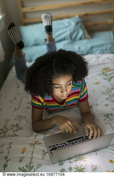 Overhead view of an ten year-old bi-racial girl working on laptop