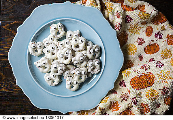 Overhead view of anthropomorphic cookies in plate on table by textile