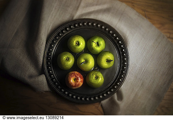 Overhead view of apples in plate on textile over table