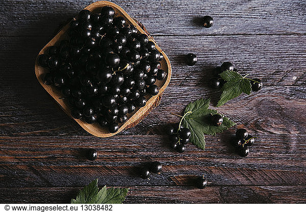 Overhead view of black currants in container on wooden table